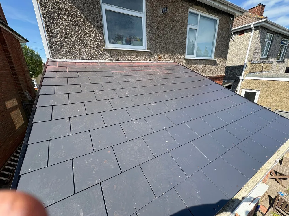 Low-pitch extension roof finished in man-made slate with new lead against the house wall