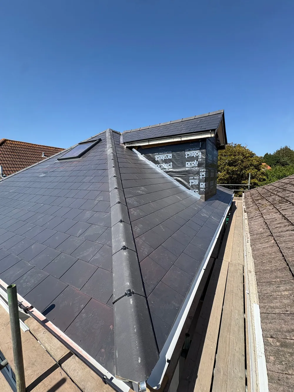 After: the same roof in new Jutland Graphite slate with a new Velux window, dry ridge and the chimney dropped below roof level