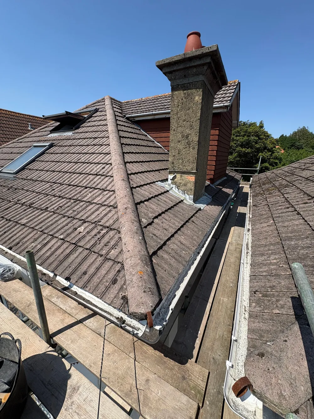 Before: tired brown concrete tiles with an old chimney stack and worn roof window