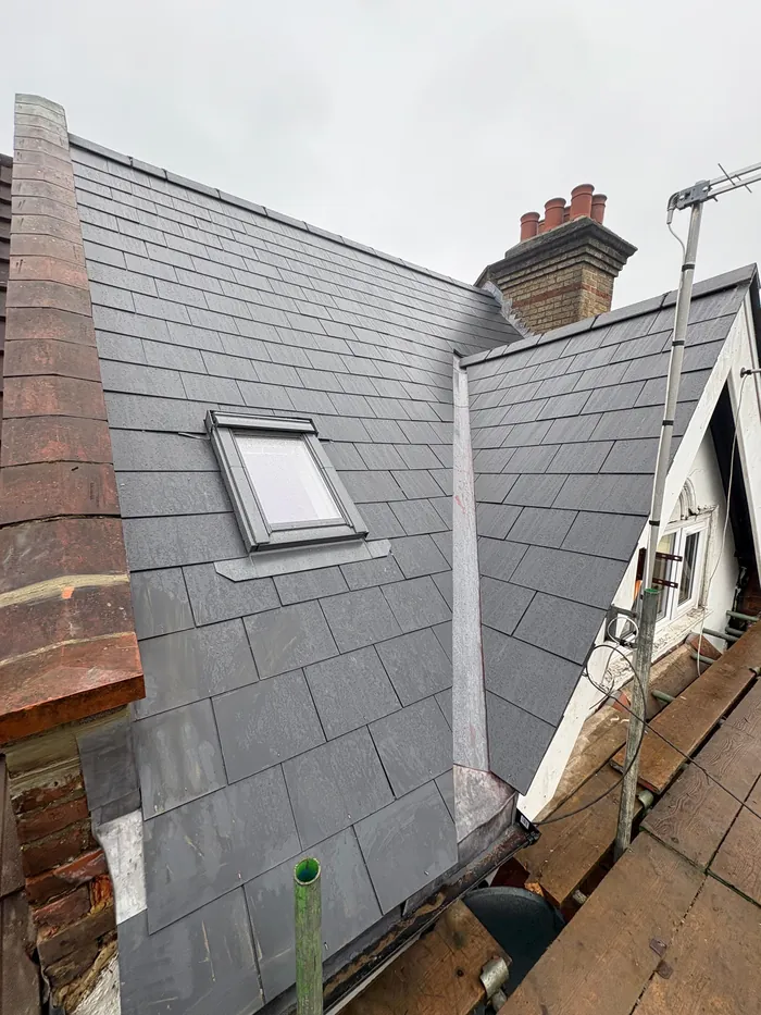 New slate roof with a Velux roof window fitted and a chimney stack behind